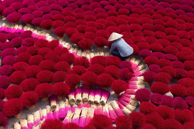 A worker toils away amongst the thousands of sticks of incense in Quang Phu Cau, Vietnam.