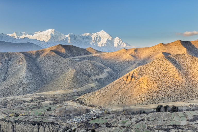 Looking over the wild and desolate landscape of Upper Mustang in Nepal to the Nilgiri Himal mountain range. Part of the Annapurna massif, Nilgiri Himal is composed of three peaks with the highest standing at 7061m.